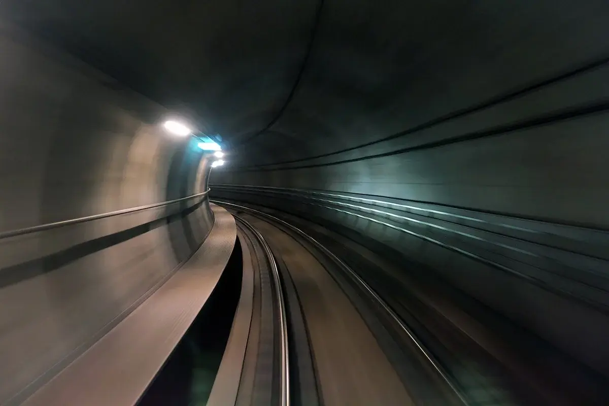 A curved underground metro tunnel with tracks and lights.