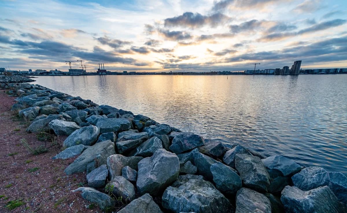 Rocky shoreline and city skyline at sunset in Copenhagen