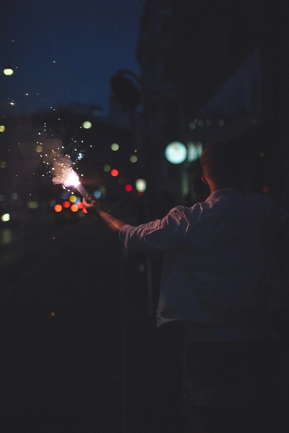 A person holds a sparkler at a night festival.