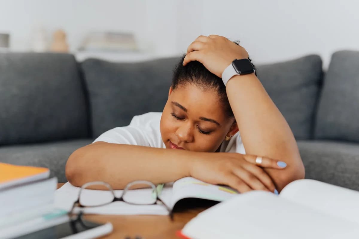 Woman resting head on open books at table