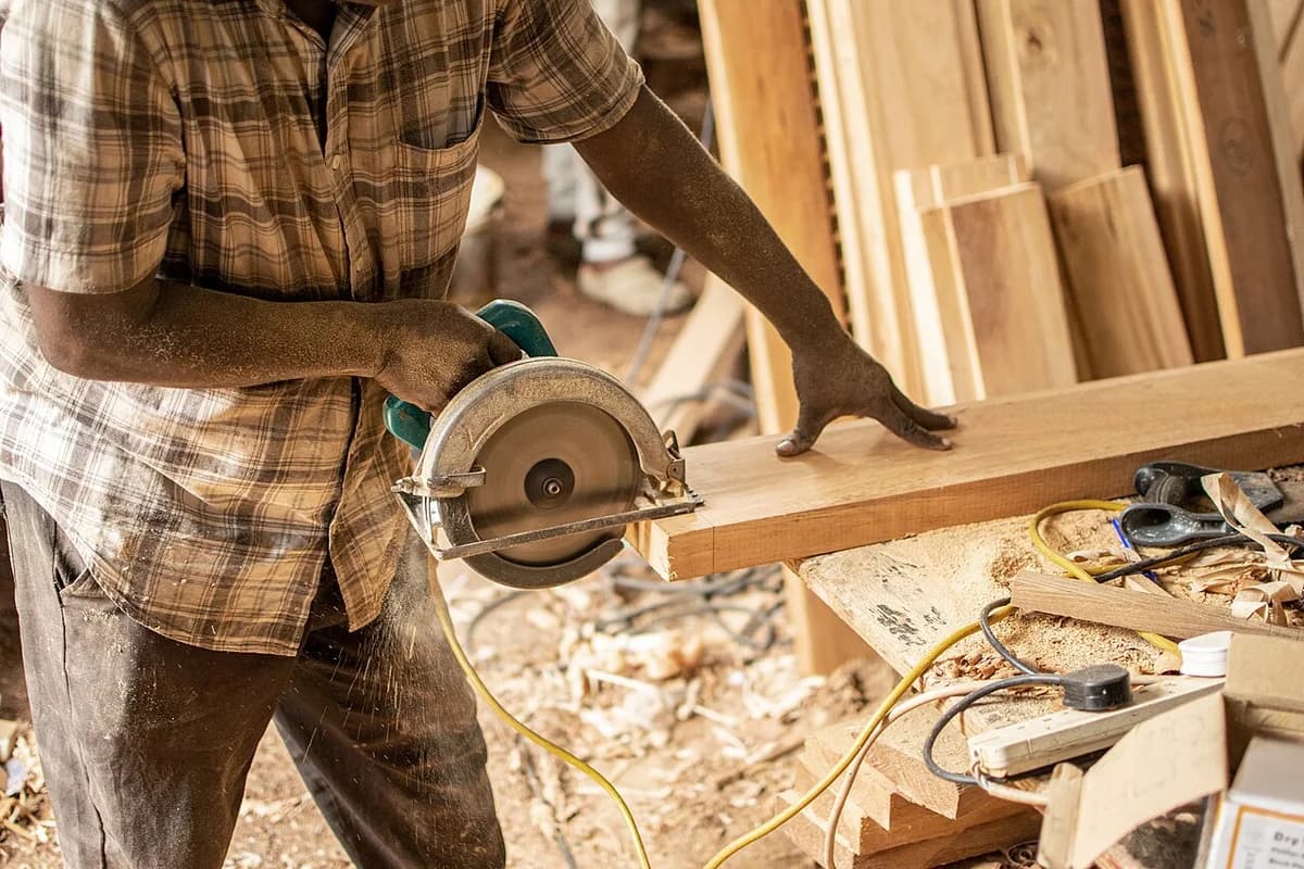 Person cutting wood with circular saw in workshop