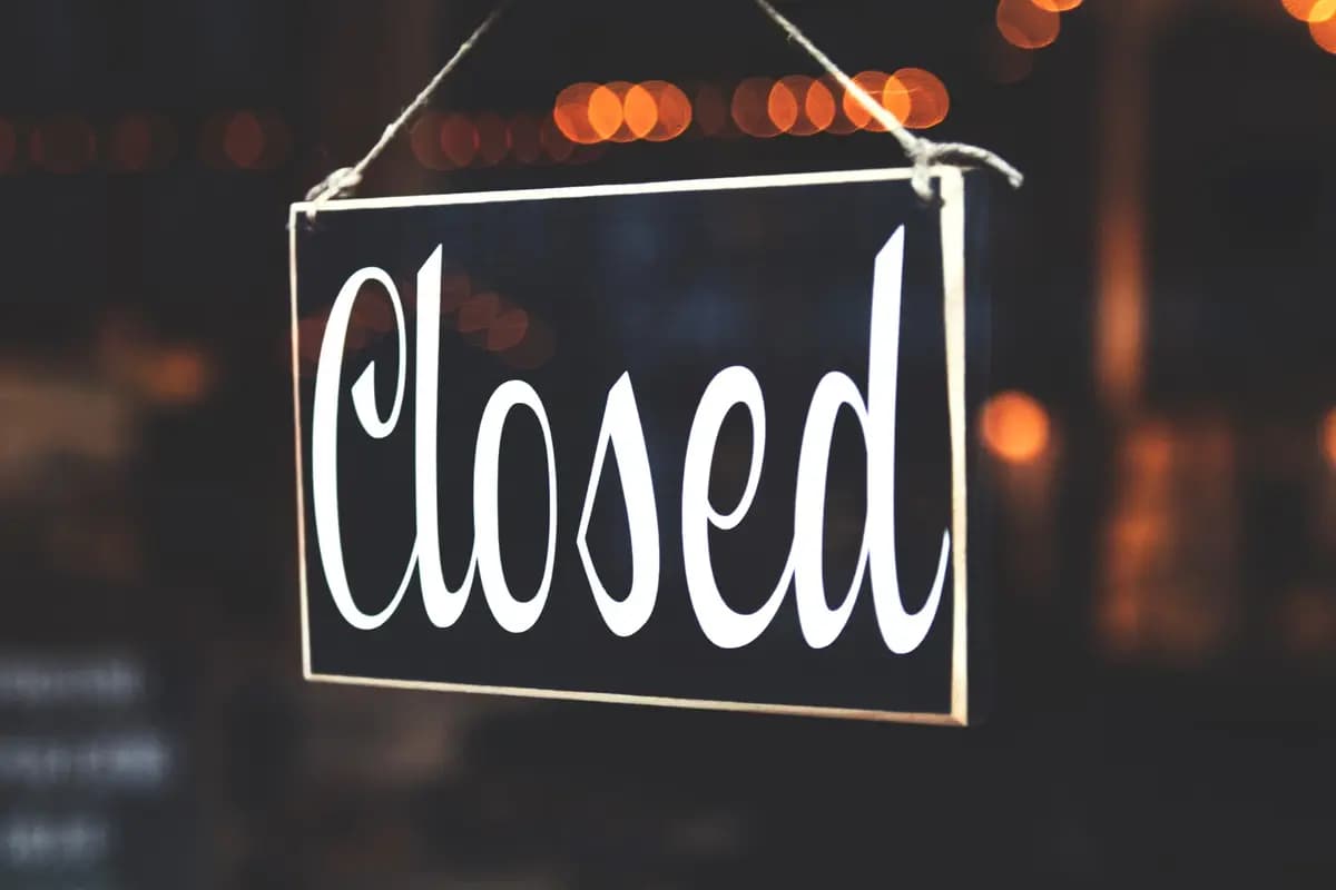 A close-up of a 'Closed' sign hanging against a blurred, bokeh background, creating a warm, inviting atmosphere.