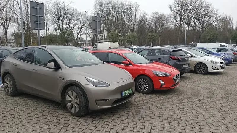 Several cars parked in a lot on a cloudy day