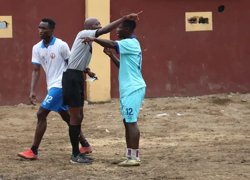 Football players and referee arguing on football field
