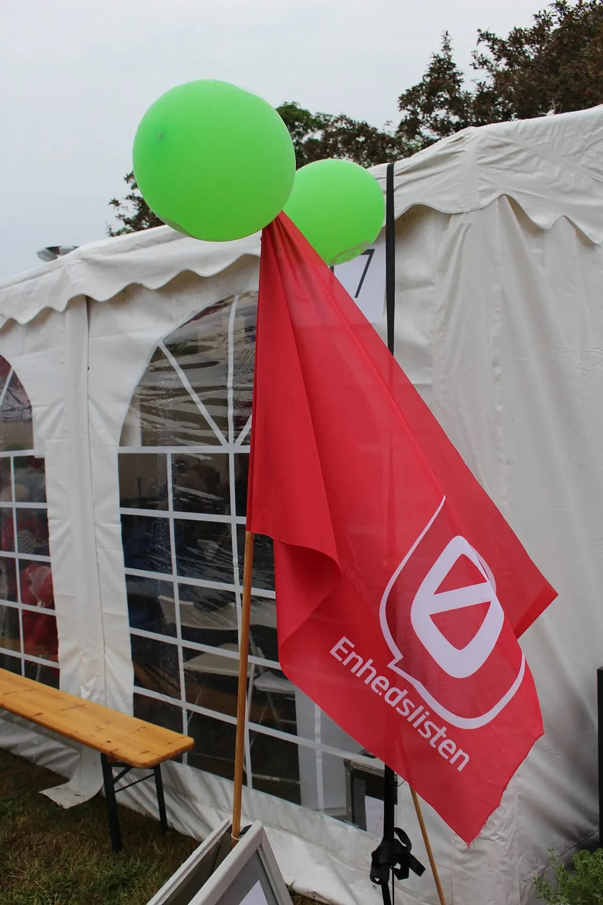Red Enhedslisten flag with green balloons in front of tent