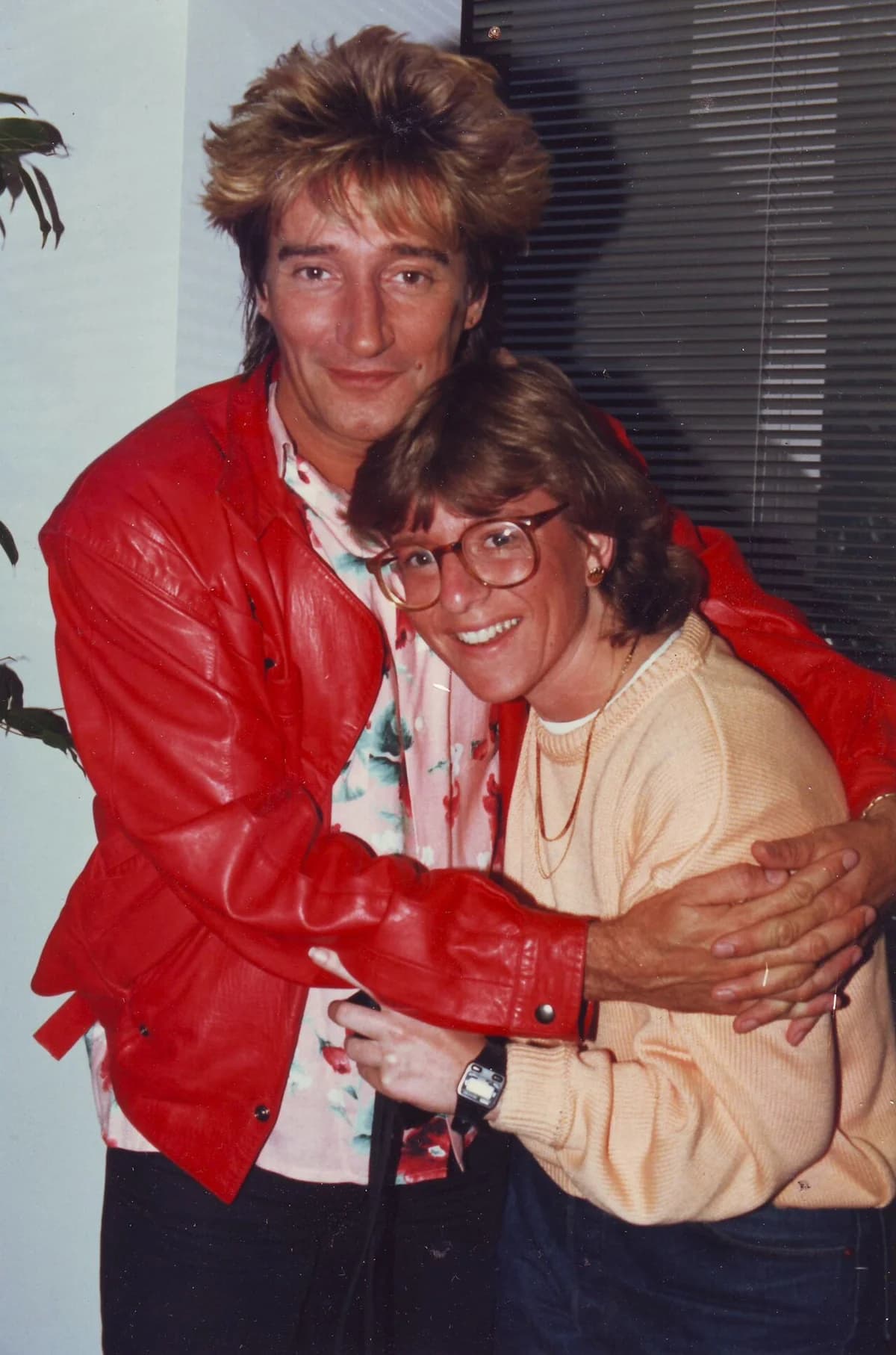 Rod Stewart poses with a smiling woman indoors.