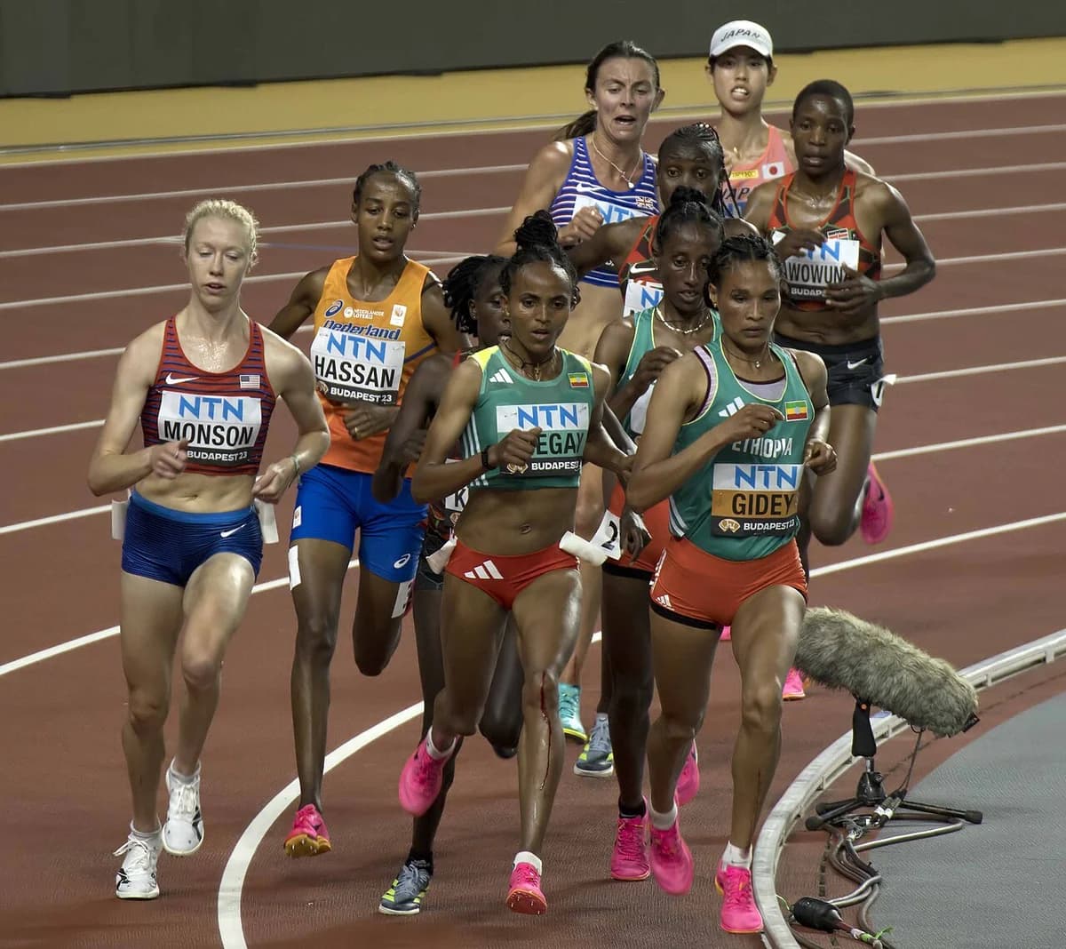 A tight pack of female runners competing in a 10,000-meter track race.
