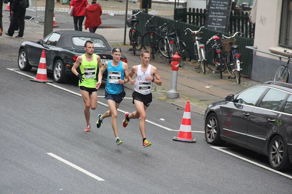 Three male runners racing in a street marathon in Copenhagen.