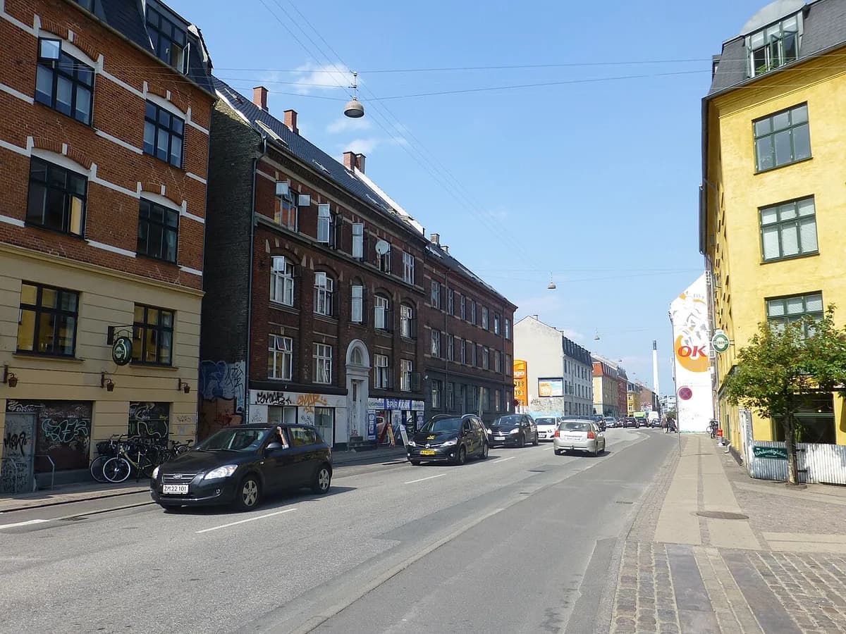 A Copenhagen street with apartment buildings and cars on a sunny day.