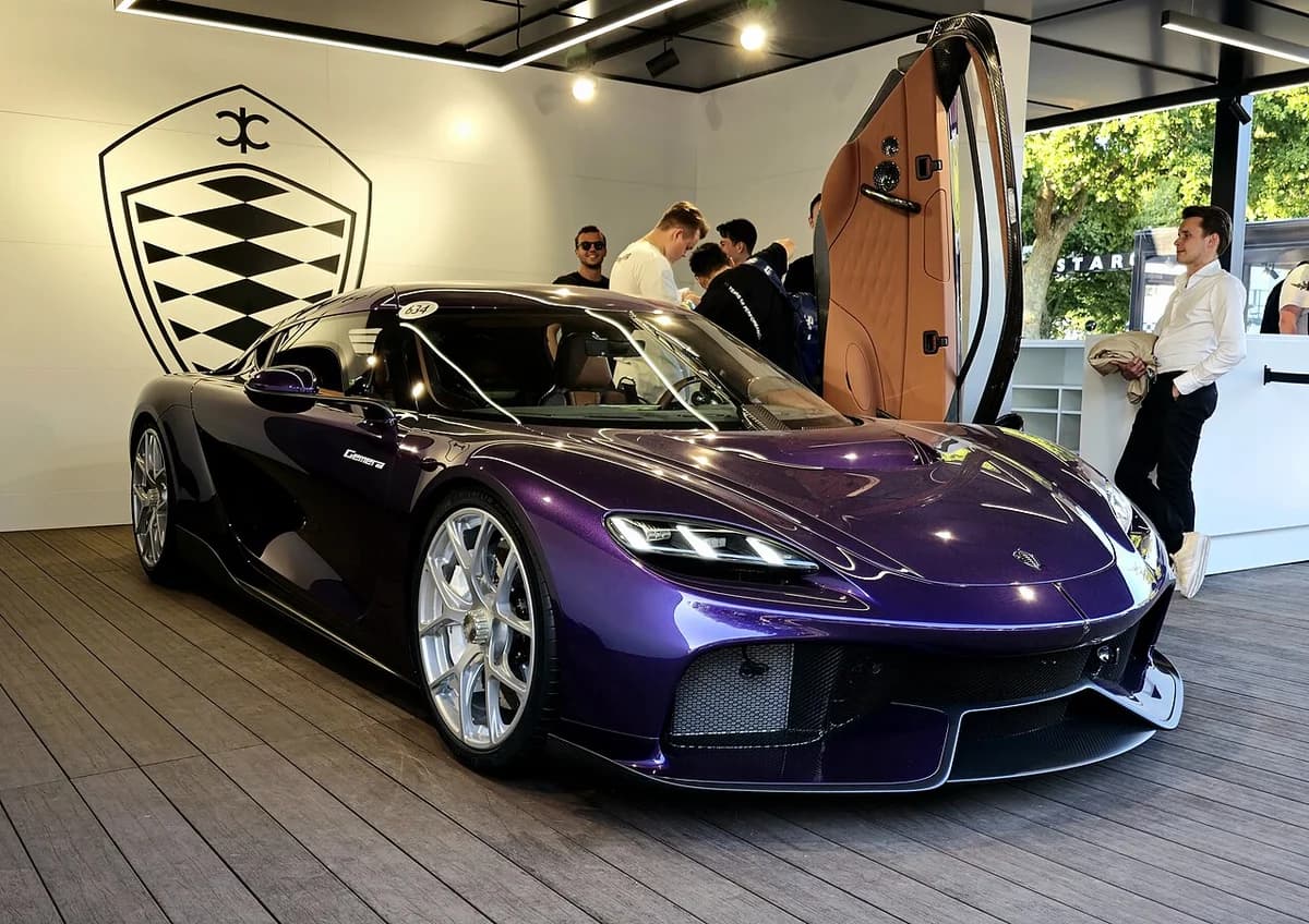Front view of purple Koenigsegg Gemera with showroom background and people