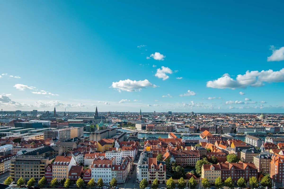 Panoramic view of Copenhagen with red-roofed buildings under a blue sky.