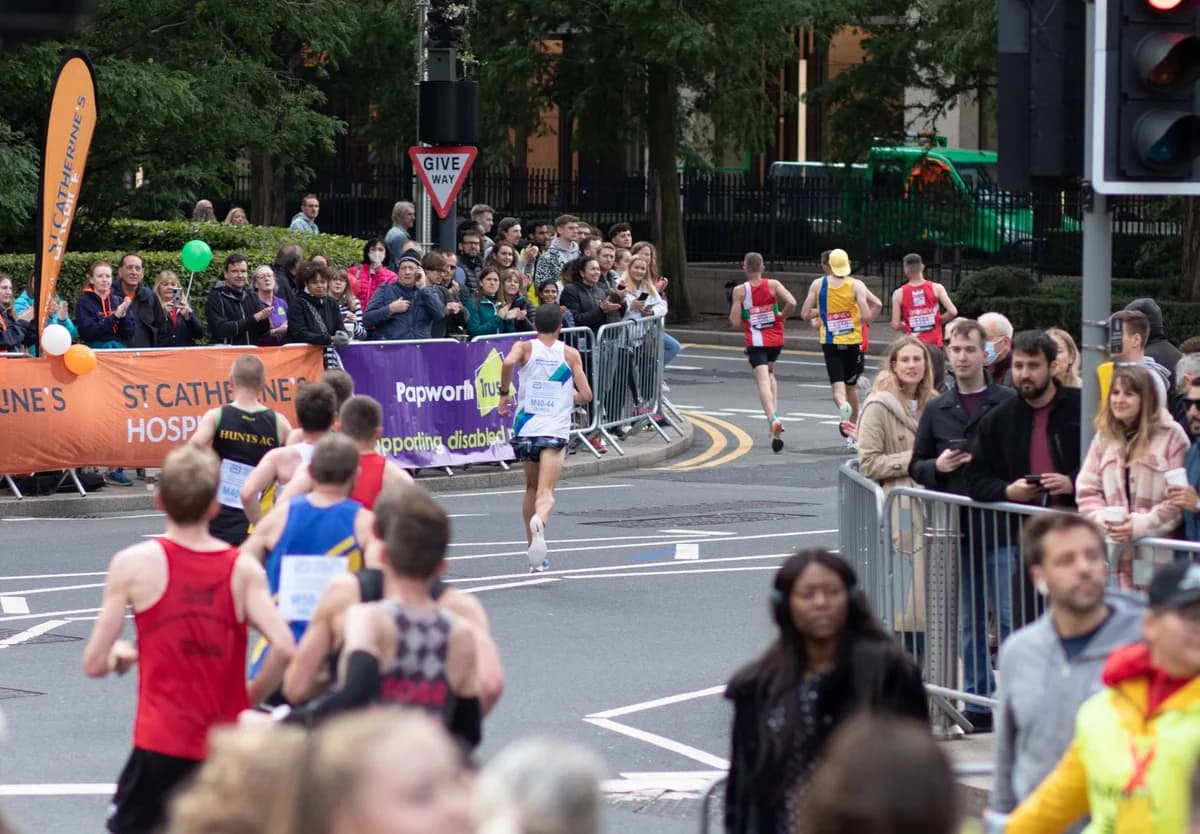Marathon runners pass spectators lining a city street