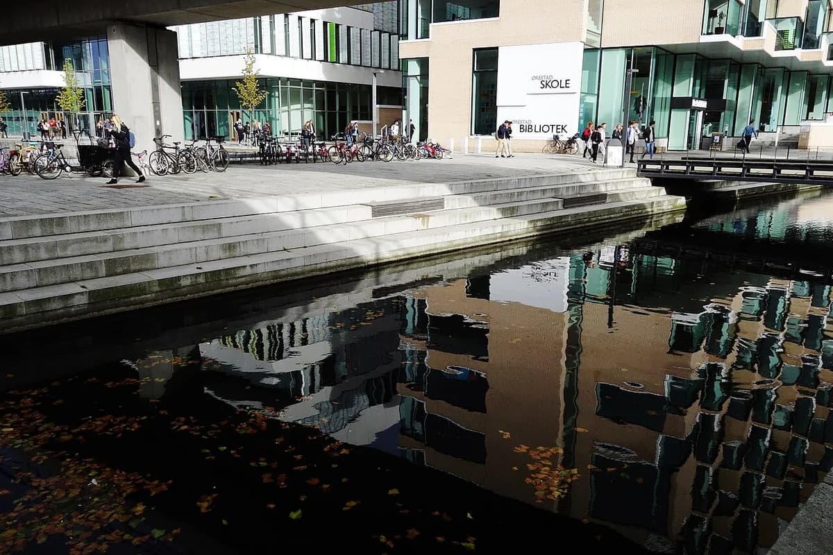 Modern buildings and canal in Ørestad City with people and bicycles