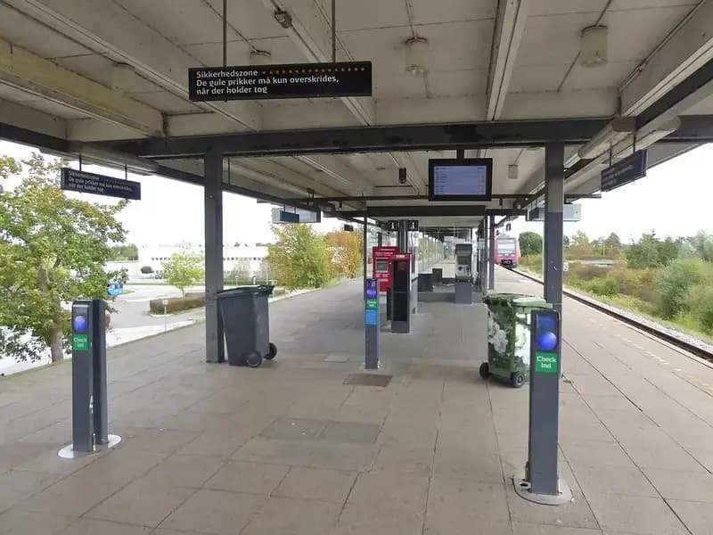 Empty train station platform with ticket check-in machines and a train in the background
