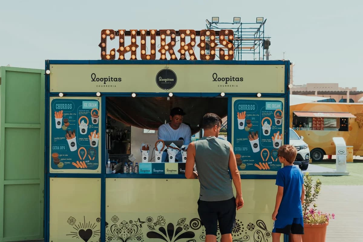 A father and son order churros at an outdoor food stall in Dubai.
