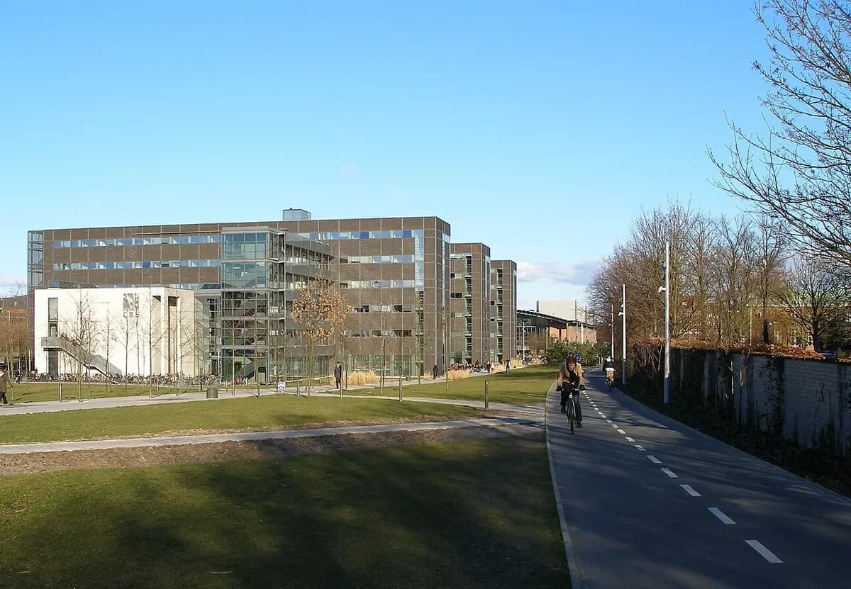 Modern building of Copenhagen Business School next to a cyclist on a bike path