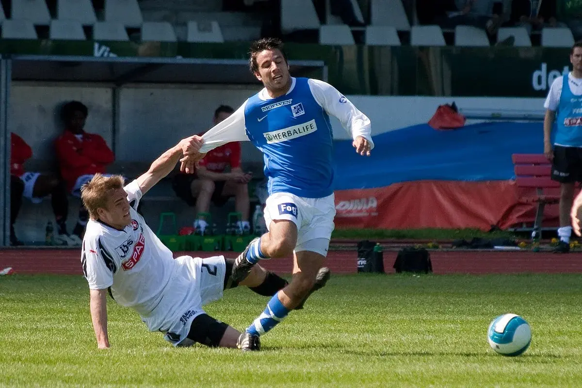 Two football players battling for the ball during a Danish match.