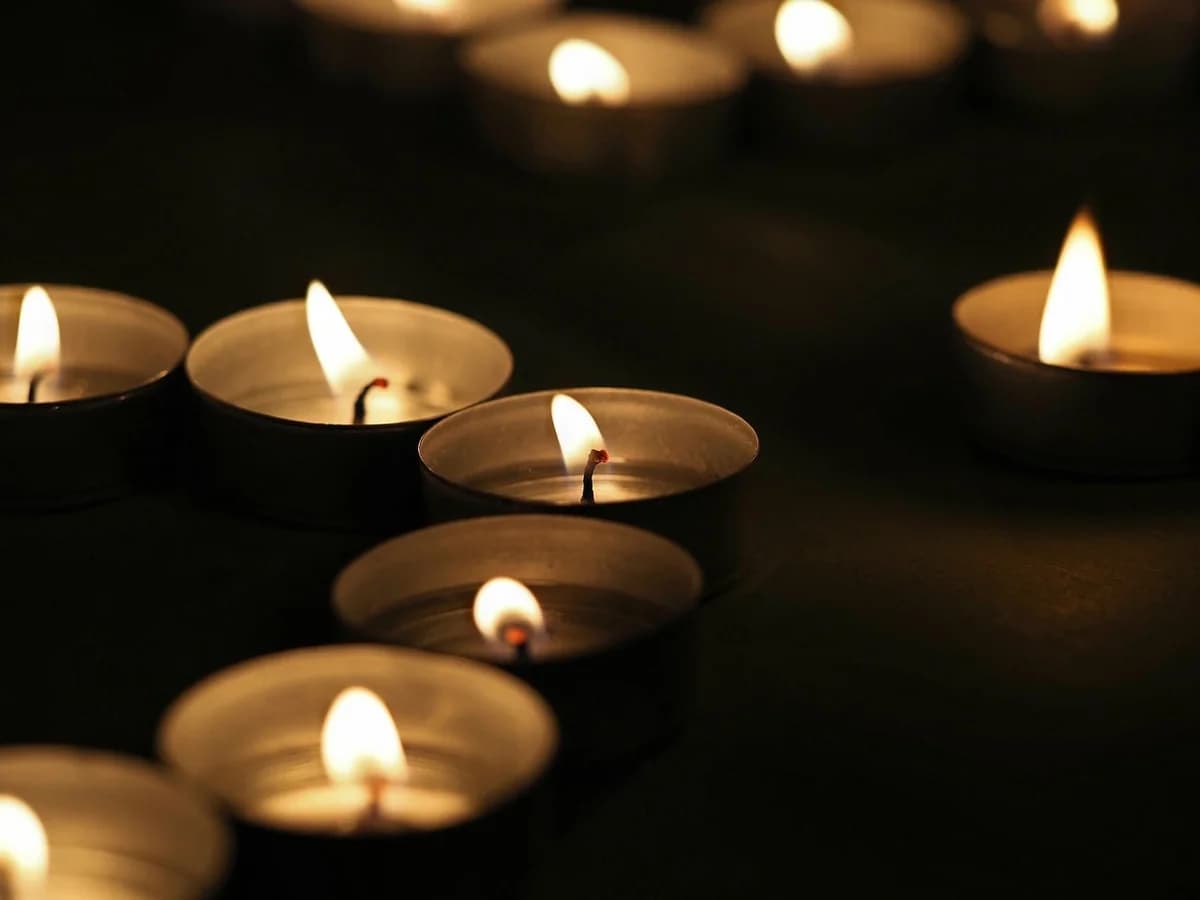 Several lit tealight candles in a dark, calm setting