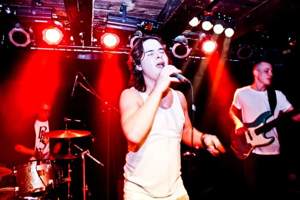 Singer and band performing on stage with red lights